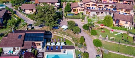 An aerial view of a residential area with houses, a swimming pool, and a small park.