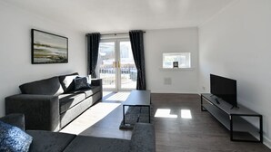 A modern living room with a sofa, a coffee table, and a TV on a stand.