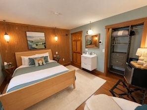 A bedroom with a wooden bed, bedside tables, a nightstand, a dresser, a mirror, a wardrobe, and a chair.