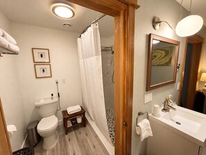 A bathroom with a toilet, sink, shower, and a towel rack.