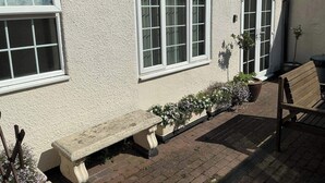 A building with a stone bench, a potted plant, and a wooden bench outside. - Rain Hill Cottage - Sleeps 4, Parking & Pets Ok (Louth)