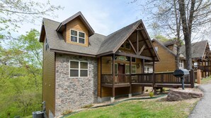 A lodge with a stone facade, wooden deck, and a covered porch. - Coyote Cabin (Branson)