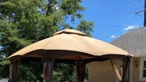 Um terraço coberto ao ar livre com guarda-corpo branco e toldo.