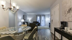 A modern living room with a glass dining table, sofas, and a chandelier. - Glam R Us (Branson)