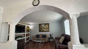 Ein Wohnzimmer mit Holzboden, einer Couch, einem Couchtisch und einer Wanduhr.