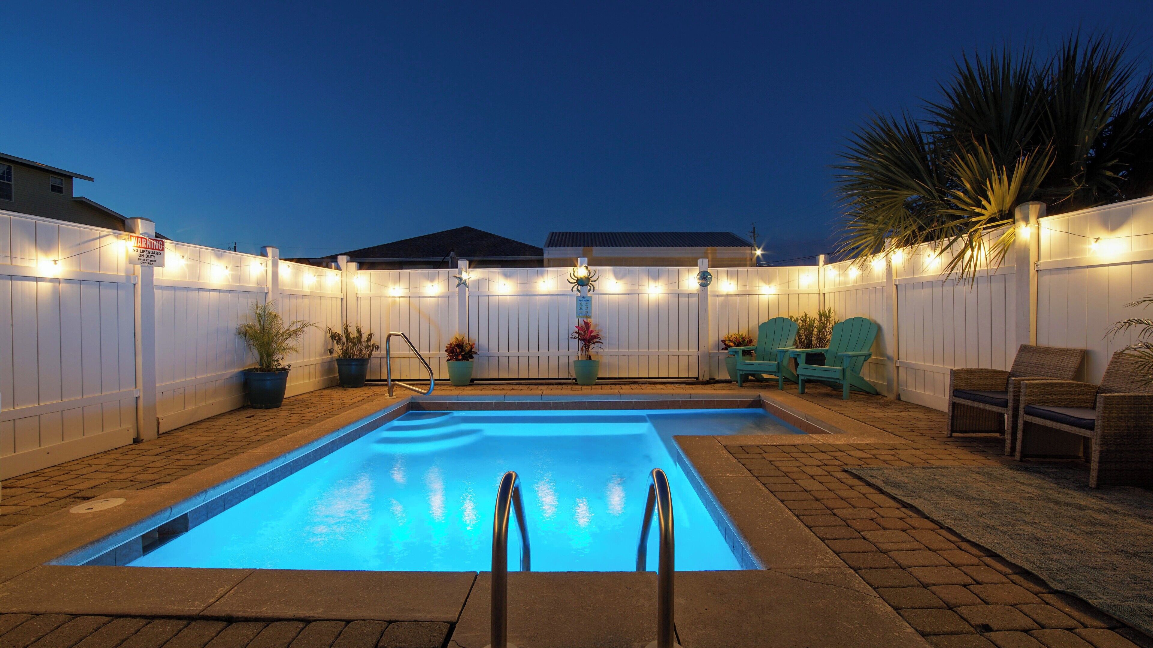 A backyard with a swimming pool, potted plants, and outdoor seating.