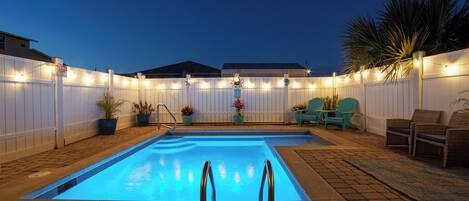 A backyard with a swimming pool, potted plants, and outdoor seating.