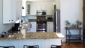 Una cocina moderna con una isla central, electrodomésticos de acero inoxidable y una pared de acento de piedra.