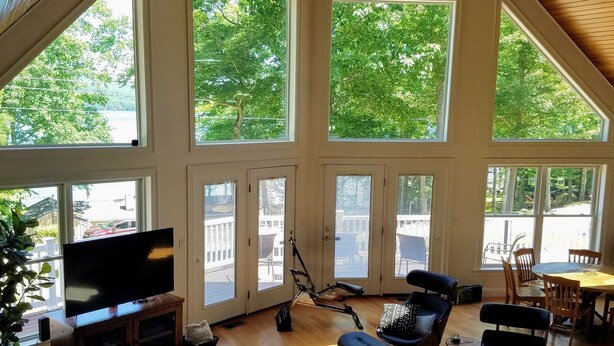 Amplia sala de estar con un televisor grande, asientos cómodos y vistas a árboles a través de ventanas amplias.