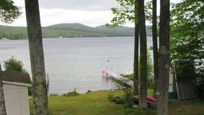 Vista de un lago con un muelle, árboles y un cobertizo pequeño.