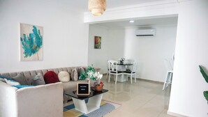 Un salon moderne comprenant un canapé, une table basse et un coin repas avec des chaises.