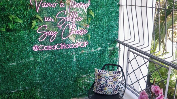 Un balcon agrémenté d’un mur végétal, d’une suspension lumineuse, d’une petite table avec un pot de plante et d’une chaise avec un coussin à motifs.