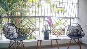Un balcon avec deux chaises, une petite table et une plante en pot.