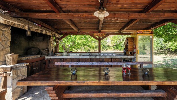 A rustic outdoor bar area with stone walls, wooden beams, and a stone fireplace. - Little Castle by Interhome (Skradin)