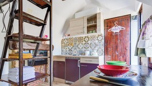 A kitchen with a wooden table, a hanging clothes rack, and a tiled backsplash. - Little Castle by Interhome (Skradin)