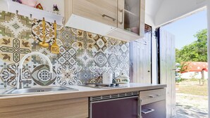 A modern kitchen with patterned tiles, stainless steel appliances, and wooden cabinets. - Little Castle by Interhome (Skradin)