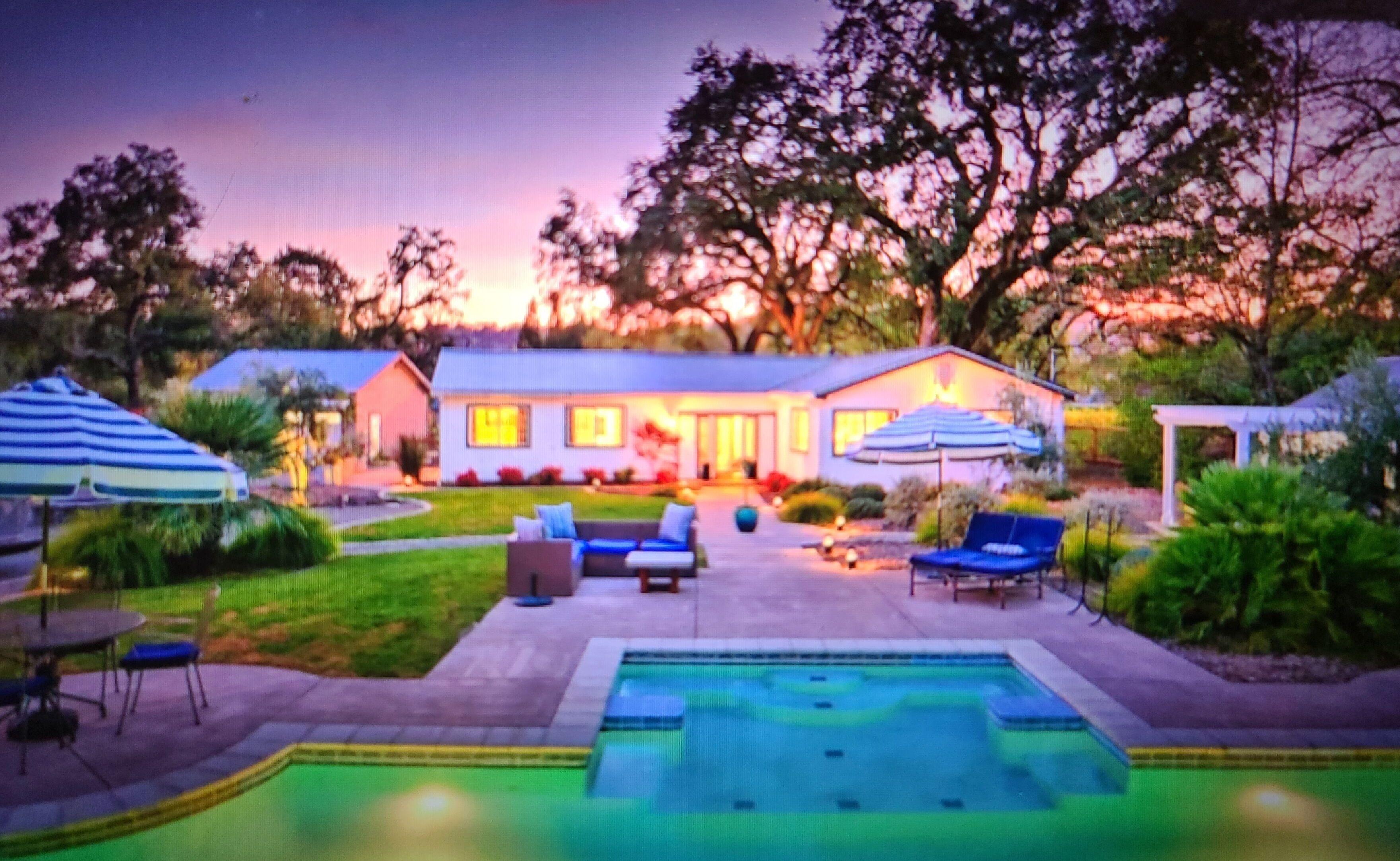 Une maison avec une piscine, du mobilier d’extérieur et un espace patio.
