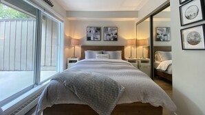 A bedroom with a large bed, bedside tables, a window, and artwork on the walls. - Whistler Village Townhome (Whistler)