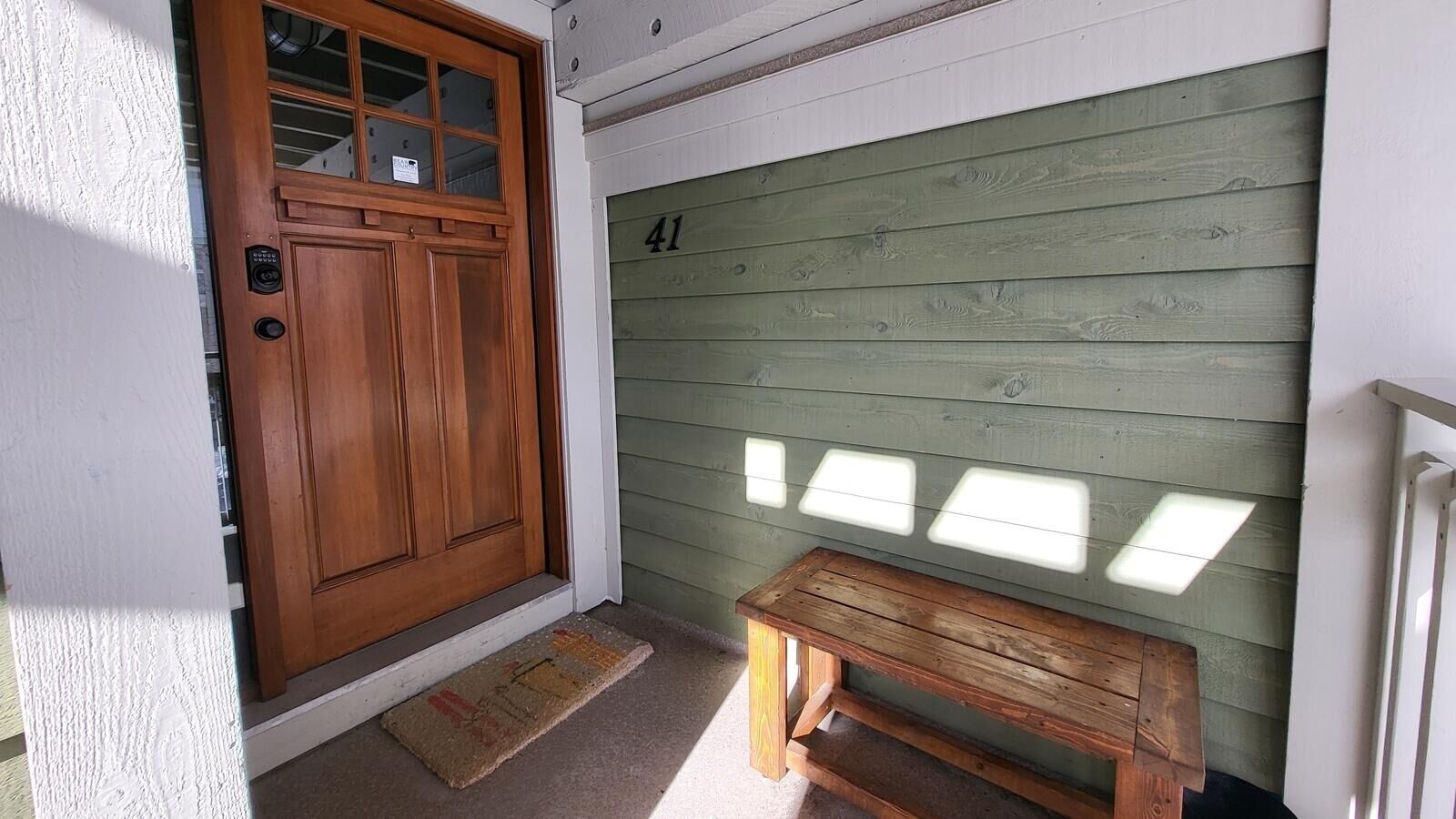 A wooden door with a glass panel, a wooden bench, and a garage door with the number 41.