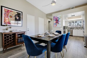 Un comedor moderno con una mesa oscura, sillas azules y una estantería para vinos.
