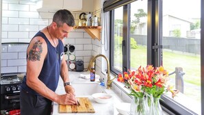 A modern kitchen with a large island, a gas stove, and a window with a view of the outside. - The Pirate's Rest, a tiny home by the beach. (Pauanui)