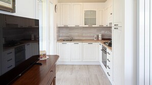 Una cocina moderna con armarios blancos, encimera de madera y horno integrado.