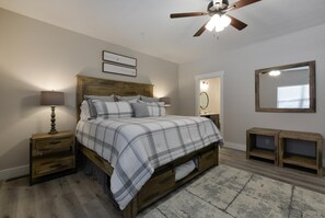 A bedroom with a wooden bed, nightstands, a ceiling fan, a mirror, and a rug. - Journey's Remedy (Branson)