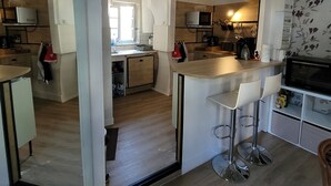 A modern kitchen with a central island, bar stools, and a microwave. - Appartement Historique (Bagnères-de-Luchon)