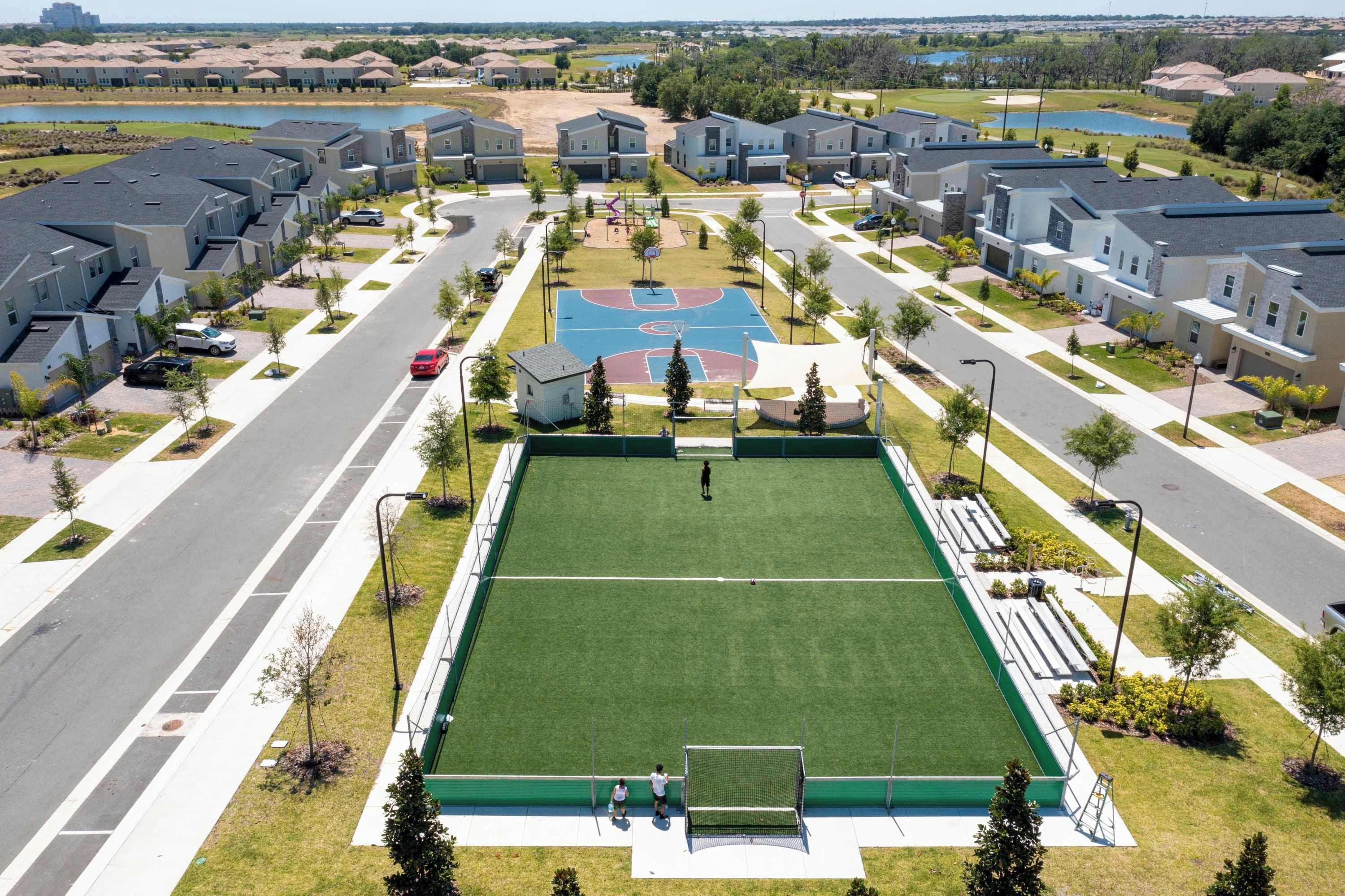 A residential area with modern houses, a central basketball court, and a well-maintained green space.