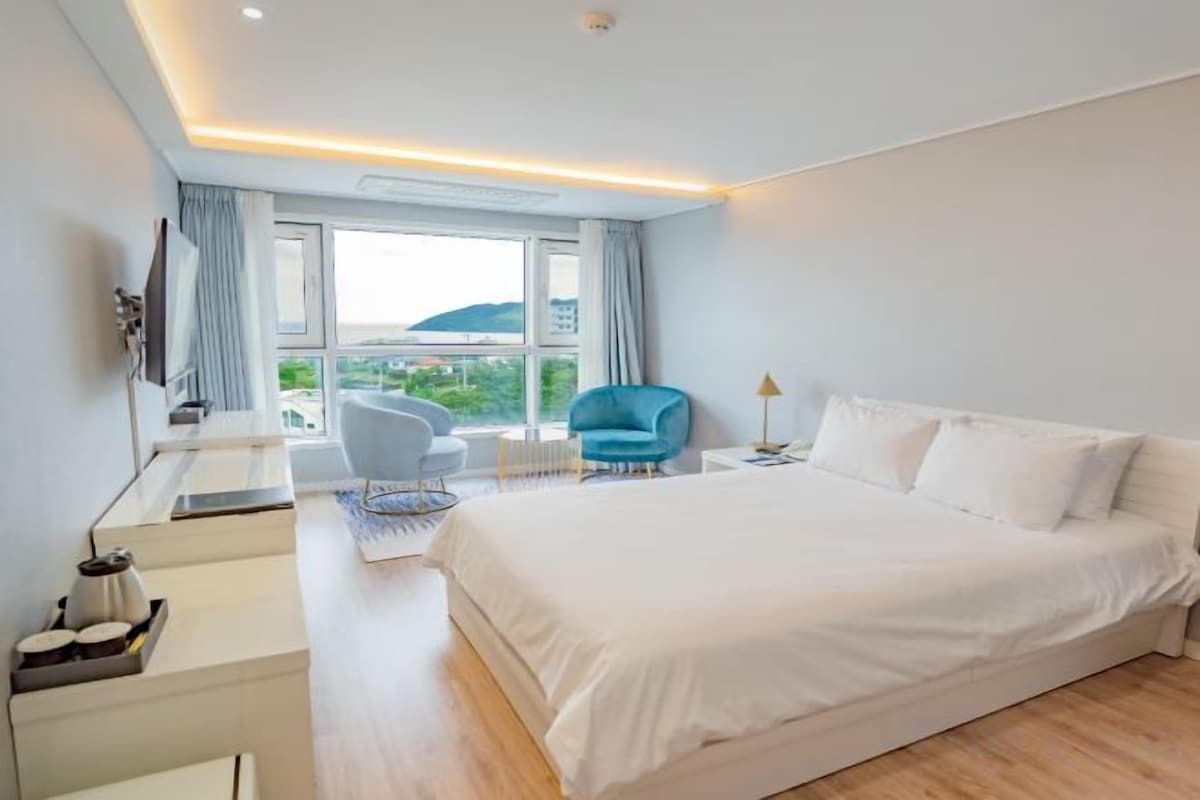 Une chambre d’hôtel avec un grand lit, un bureau avec une chaise, une télévision et une vue sur l’extérieur.