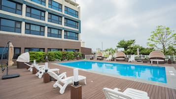 Een seizoensgebonden buitenzwembad en ligstoelen