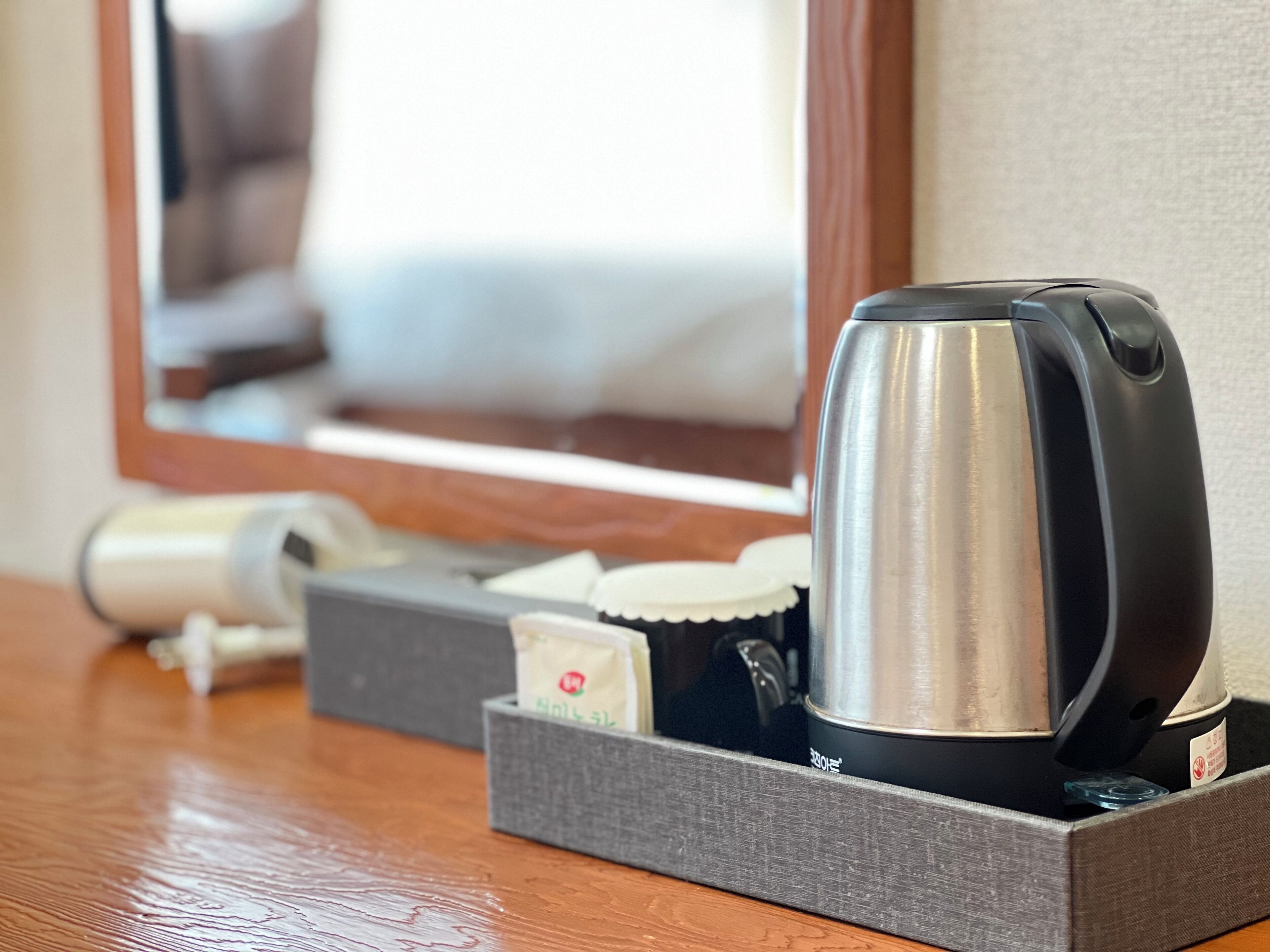 Ein Hotelzimmer mit einer Kaffeemaschine, einem Föhn und einer Papiertauschbox auf einem Holztisch.
