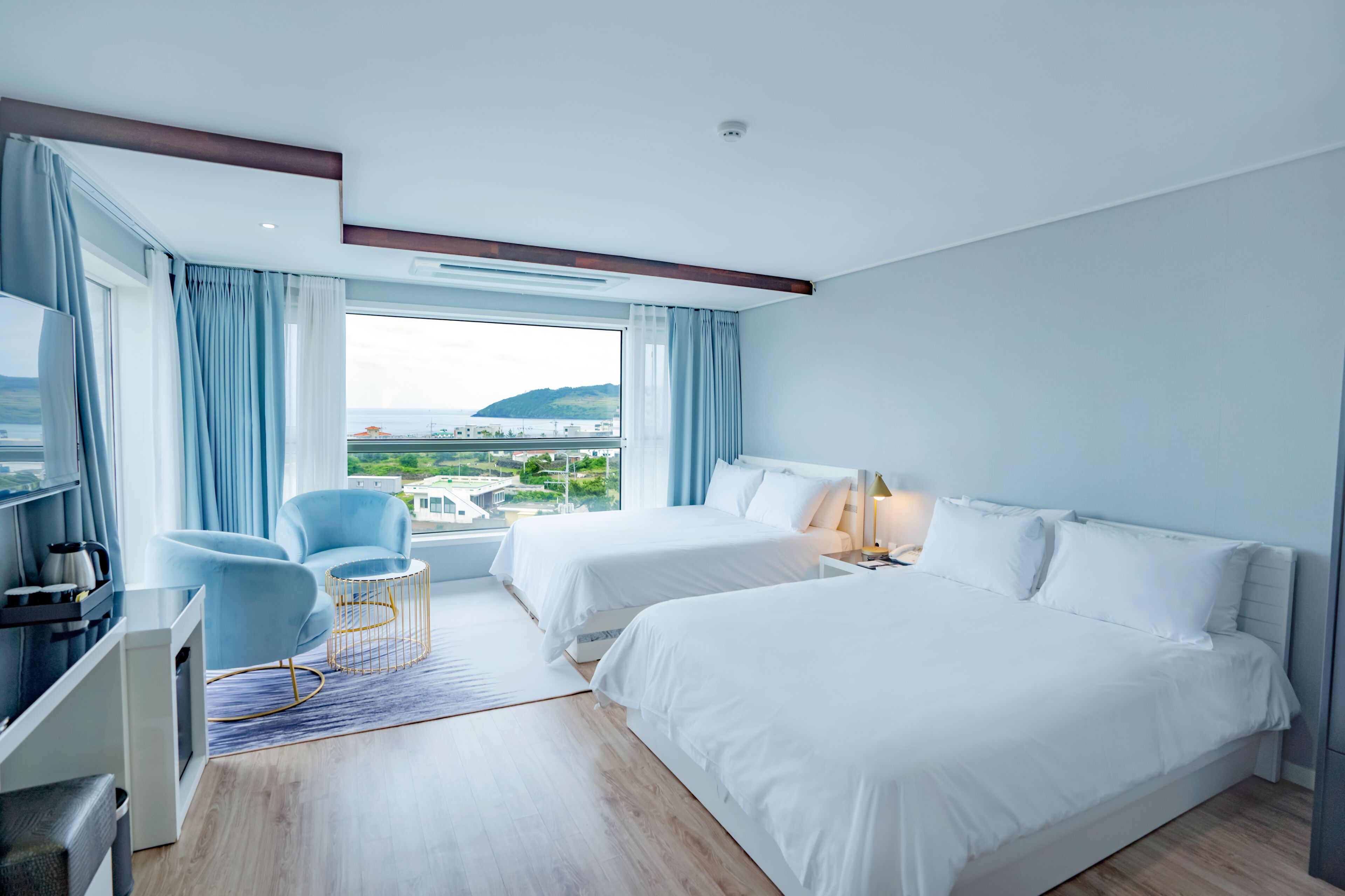 Une chambre d’hôtel moderne avec deux lits, une télévision, un bureau et une vue sur la ville.