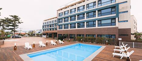 Um edifício moderno com piscina e espreguiçadeiras.