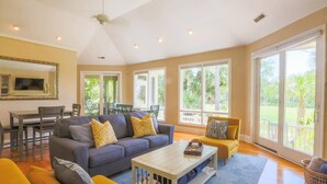 A spacious living room with a gray sofa, yellow armchairs, a white coffee table, and large windows offering a view of the outdoors. - Gorgeous Natural Light, Vaulted Ceilings & Fairway Views.  Back Deck & Screened Porch. (Kiawah Island)