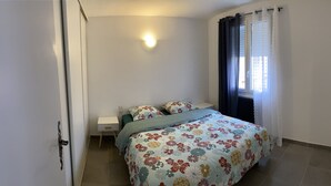 A bedroom with a bed, a nightstand, a wall-mounted light, and a window with curtains. - Joli T2 Climatis? Nimes Proche Gare et Centre Ville (Nîmes)