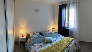 A bedroom with a bed, two bedside tables, a lamp, and a window with curtains. - Joli T2 Climatis? Nimes Proche Gare et Centre Ville (Nîmes)