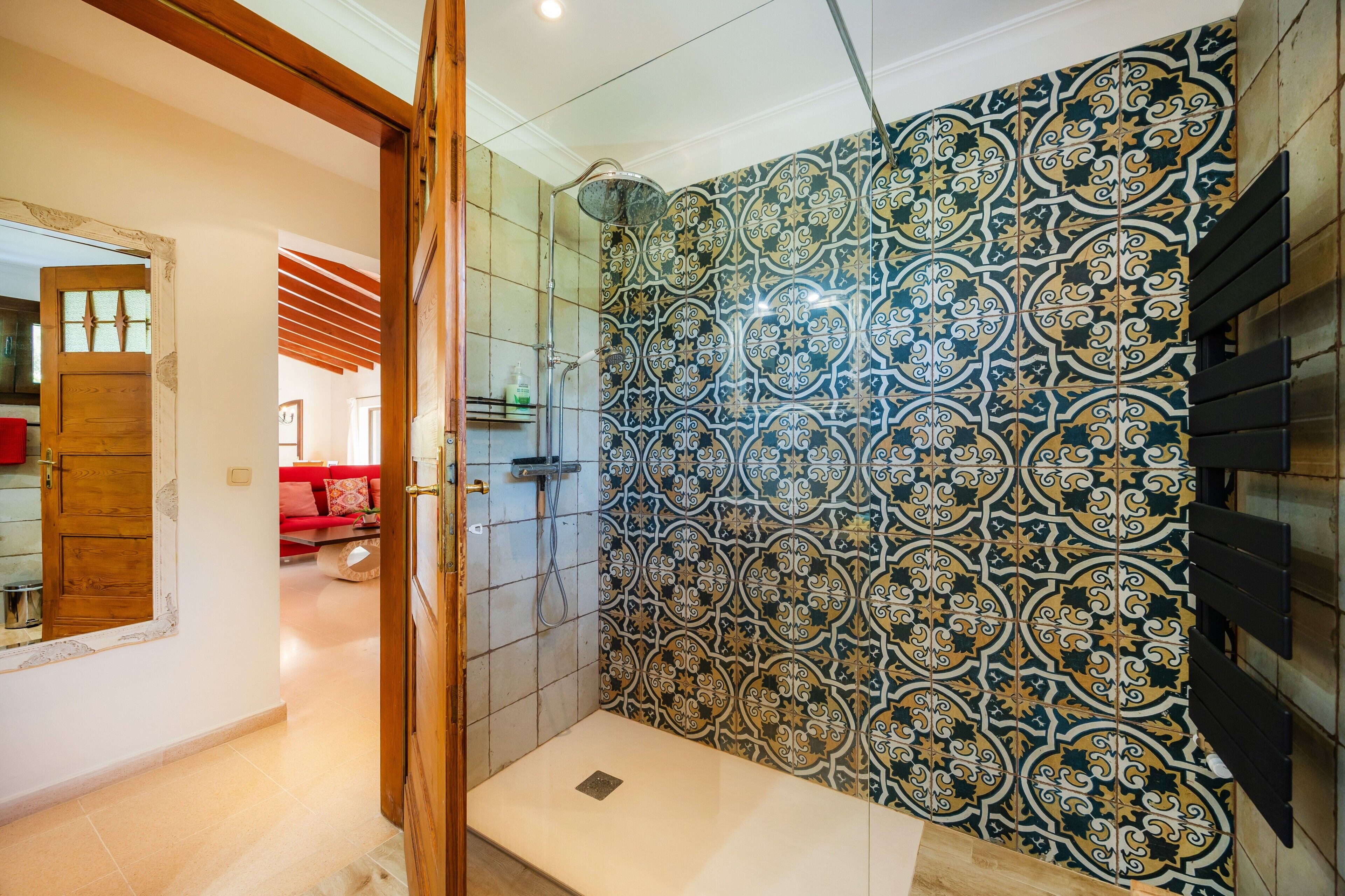A bathroom with patterned tiles, a shower, and a wooden door.