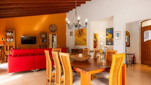A dining area with a wooden table, wicker chairs, and a red sofa.