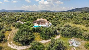 A villa surrounded by dense vegetation with a swimming pool.