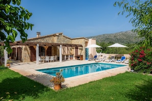 A poolside area with a stone building, outdoor seating, and a clear view of the mountains. - Villa "Finca Soliva" with Mountain View, Garden, Wi-Fi, Pool & Terrace (CAPDEPERA)