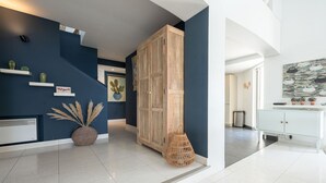 Ein modernes Interieur mit einer dunkelblauen Akzentwand, einem Holzschrank und einem weißen Konsolentisch mit Dekorationselementen.