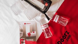 A promotional display with a RedDoorz brochure, a black mesh bag, and a water bottle on a white fabric background. - Reddoorz @ Poblacion Sur Sigma (Sigma)