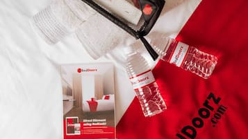 Un expositor promocional con un folleto de RedDoorz, una bolsa de malla negra y una botella de agua sobre un fondo blanco de tela.