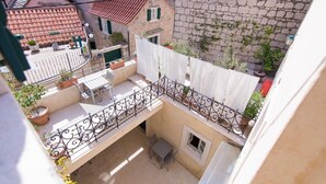 A courtyard with a table and chairs, a balcony with a railing, and potted plants. - Deluxe Studio with Balcony 302 Kovačića Street 20 (Split)