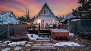 A cabin with a wooden deck, a hot tub, and a covered seating area. - Snow Daze! Visit the mountains! Bring your pup, stay, play & enjoy clean air! (Big Bear)