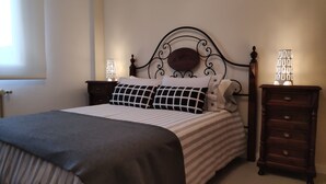 Un lit bien fait, avec une literie à rayures, une tête de lit décorative et deux tables de chevet avec des lampes.