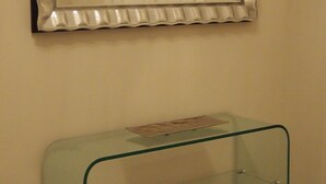 Un miroir avec un cadre décoratif, une console en verre et une porte à l’arrière-plan.