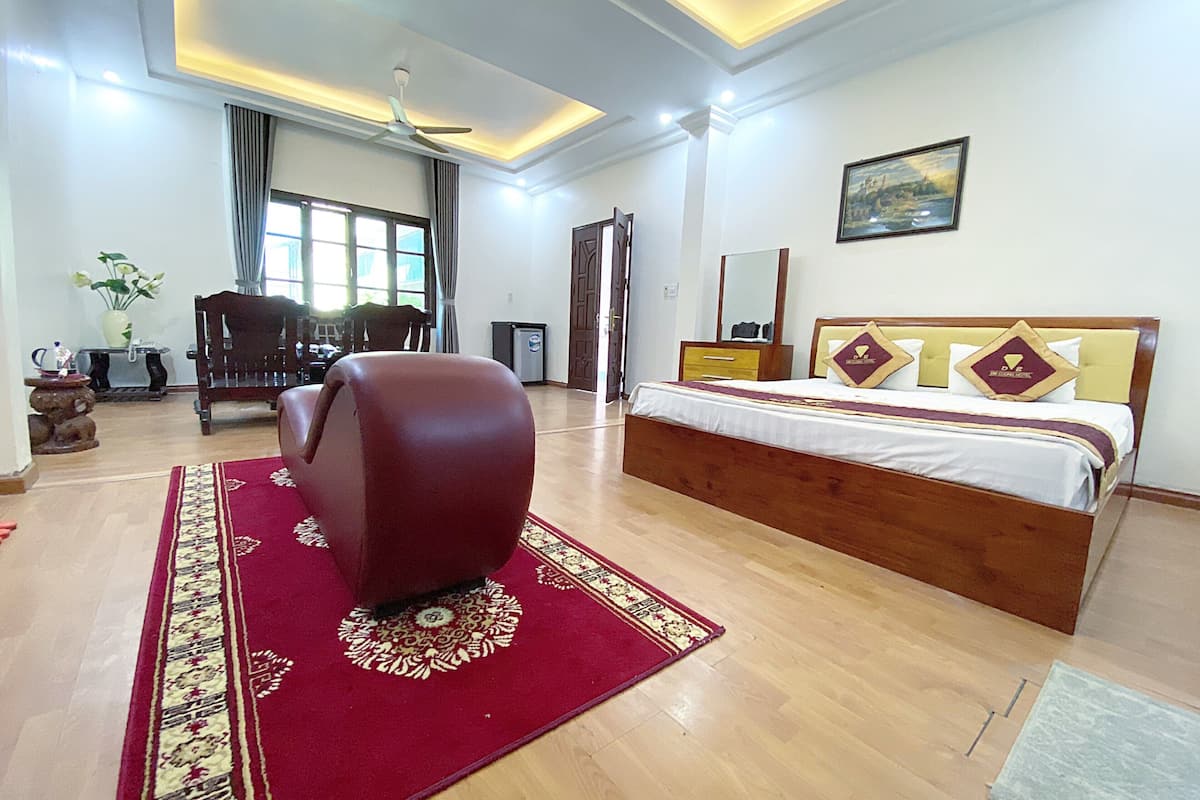 A spacious bedroom with a large bed, a wooden headboard, and a red carpet.