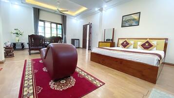 A spacious bedroom with a large bed, a wooden headboard, and a red carpet.